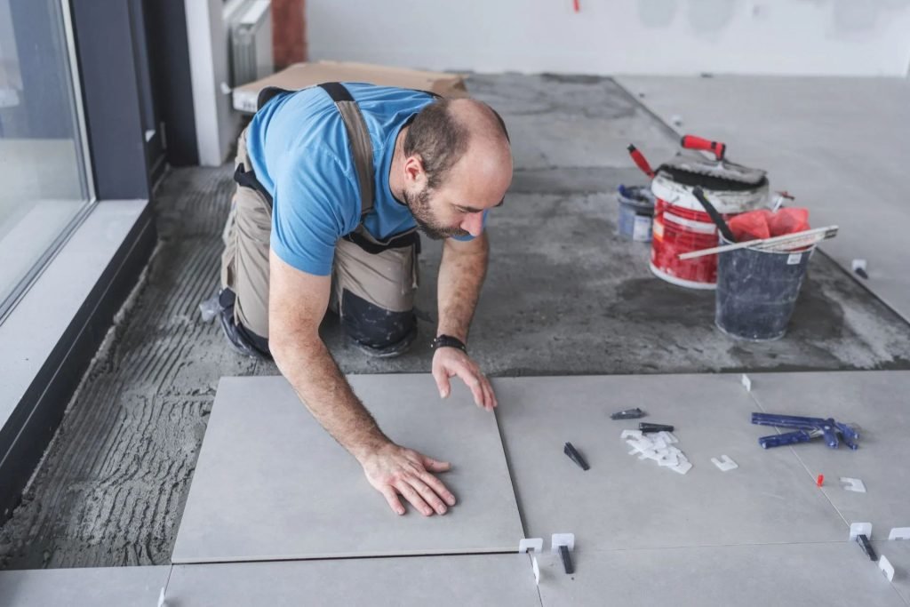 A man applying tiles to the floor, illustrating flooring services available in Columbia, SC.