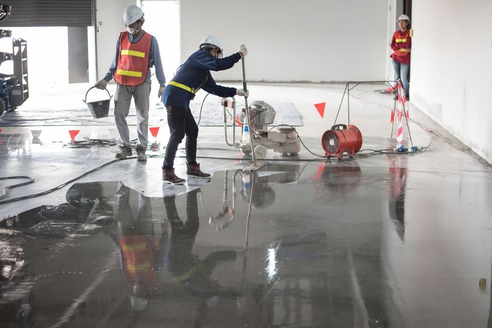 Workers engaged in pouring concrete with a machine for epoxy tile flooring services in Columbia, SC.