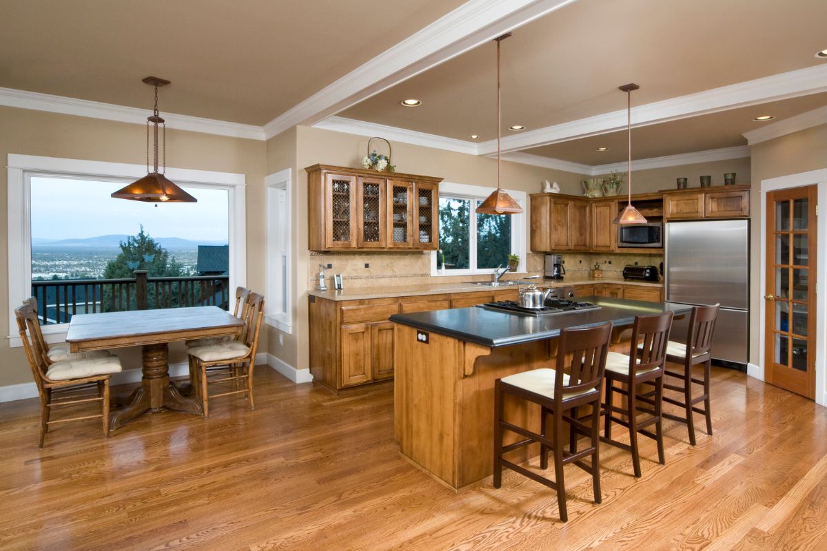  A spacious kitchen featuring hardwood floors and a large dining table, creating an inviting atmosphere for meals. 